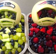 two plastic trays filled with fruit and veggies, one is made to look like football helmets