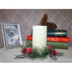 a white candle sitting on top of a table next to books and a pine cone