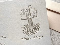 a close up of a card with a mailbox and flowers in the foreground