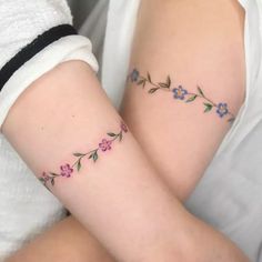 two women with matching tattoos on their arms, one is holding the other's arm