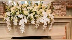 the fireplace is decorated with white flowers and greenery