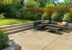 an outdoor living area with couches, tables and plants on the side of it