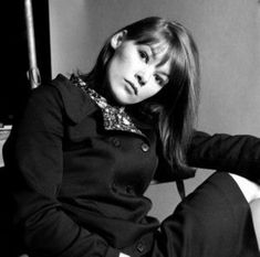 black and white photograph of a woman sitting on a chair with her legs crossed in the air