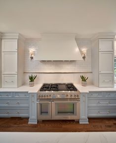 a stove top oven sitting inside of a kitchen next to white cupboards and drawers