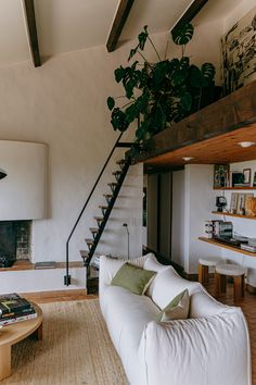 a living room filled with furniture and a staircase leading up to the top floor in front of a fire place