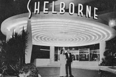 a man and woman standing in front of a building with a sign that says shelborne