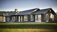 a large house with lots of windows on the front and side of it, surrounded by grass