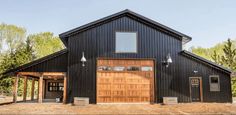 a large black barn with wooden doors and windows