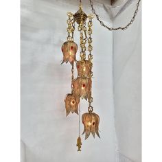 a gold chandelier hanging from a chain with red glass beads and leaves on it