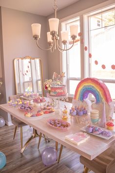 a table filled with lots of cake and candy on top of wooden tables next to windows