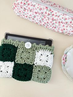 two crocheted items sitting on top of a table next to a cup and saucer