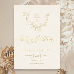 wedding stationery with gold foil flowers and greenery on the side, in front of a beige background