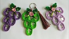 three crocheted key chains with flowers and leaves hanging from them on a white surface