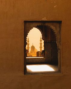 an open doorway with a view of a mosque in the distance and sunlight coming through