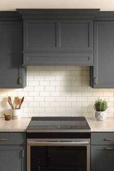 a stove top oven sitting inside of a kitchen next to gray cabinets and counter tops