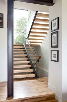 a stair case with wooden handrails and framed pictures on the wall next to it