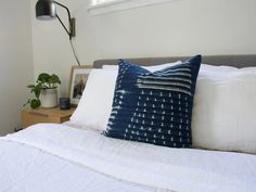 a bed with white sheets and blue pillows