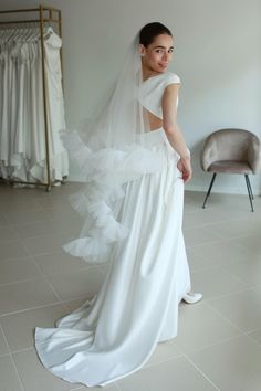 a woman in a white wedding dress looking back at the camera while wearing a veil