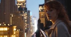 a woman standing on top of a roof next to tall buildings in the city at night