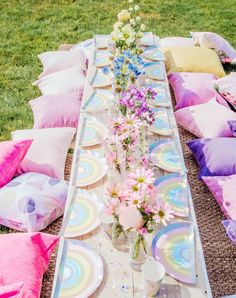 a table set up with plates and flowers on it for an outdoor party or picnic