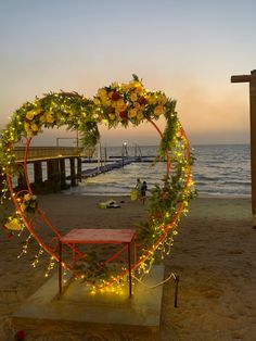 a heart shaped wreath with lights on the beach