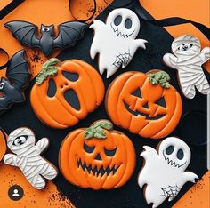 halloween decorated cookies sitting on top of a black plate with bats and jack o lanterns