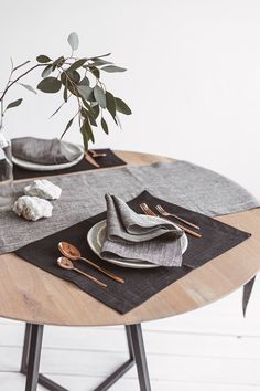 a wooden table topped with plates and napkins next to a vase filled with flowers