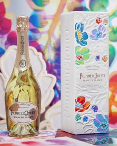 a bottle of wine next to a box on a table with flowers painted on it