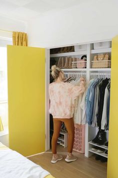 a woman standing in front of a closet filled with clothes