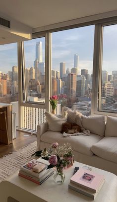 a living room filled with furniture next to large windows and a view of the city