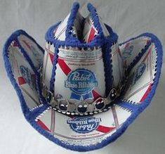 a baseball hat made out of beer cans and other items on a white tablecloth