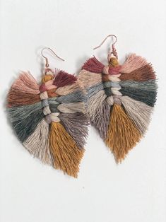 two pairs of earrings with tassels hanging from the side on a white background