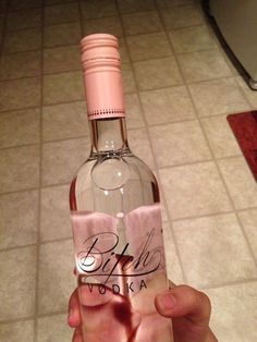 a person holding up a wine bottle with writing on the bottom and inside, in front of a tiled floor