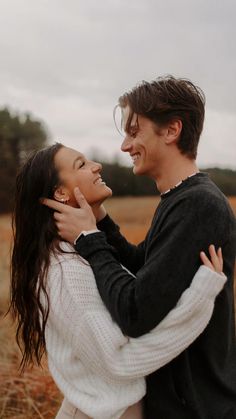 a young man and woman embracing each other in an open field