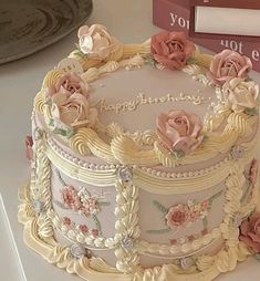 a decorated cake sitting on top of a table next to a stack of books and a clock