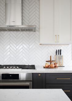 a kitchen with white cabinets and marble counter tops, stainless steel appliances and an oven