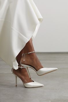 a woman's feet wearing white high heels with pearls on the ankles and ankle