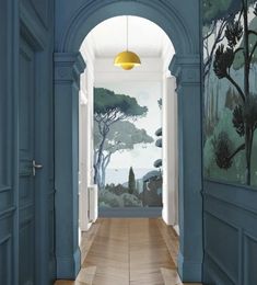 the hallway is painted in blue and has an archway leading to another room with paintings on it