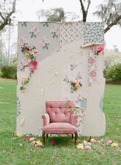 a pink chair sitting in front of a wall covered in flowers and fabric with the words,