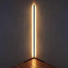 a light that is on top of a wooden floor in front of a white wall