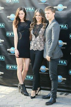 two young people standing next to each other on a red carpet