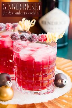 two glasses filled with red liquid and garnished with cranberries on a plate