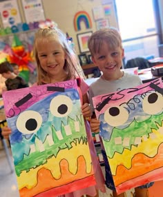 two children holding up paintings with faces painted on them