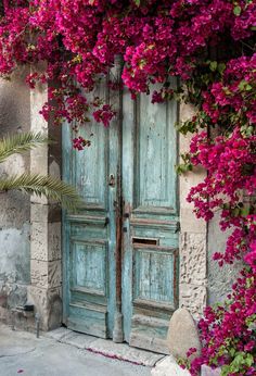 an old blue door with pink flowers growing over it