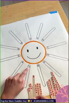 a child's hand is pointing at an art project with popsticks on it