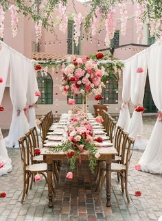 a long table is set with pink flowers and white draping on the walls