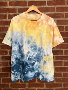 a t - shirt hanging on a brick wall with the colors blue, yellow and white