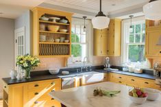 a kitchen with yellow cabinets and black counter tops, an island in front of the sink