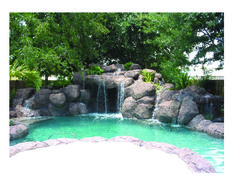 an outdoor pool with waterfall and rocks