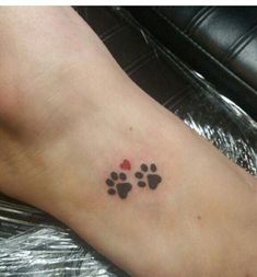 a small paw print on the foot of a person with a red and black heart